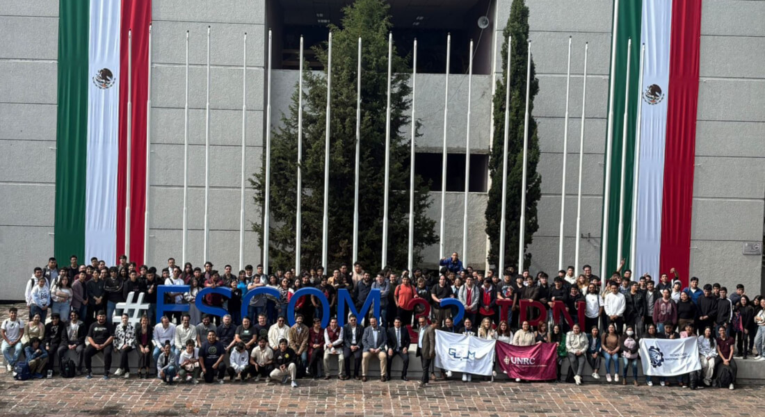 Group photo of hackathon students, mentors, and judges in front of the large #ESCOM letters and the Mexican flag.